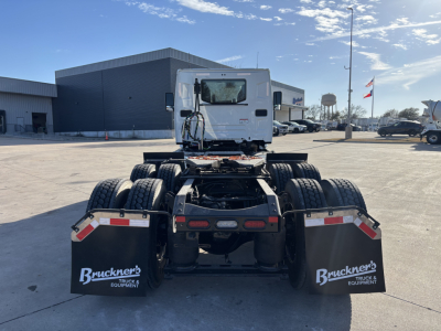 Conventional daycab truck chassis rear view showing dual rear axles and mud flaps with Bruckner's logo.