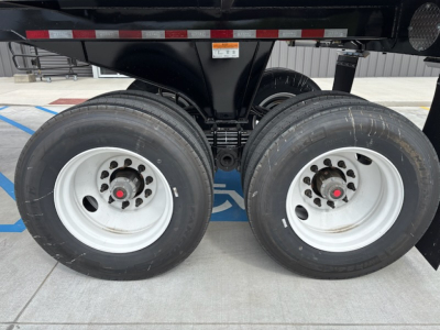 Dual rear trailer wheels with white rims and black tires, undercarriage showing suspension and axle assembly.