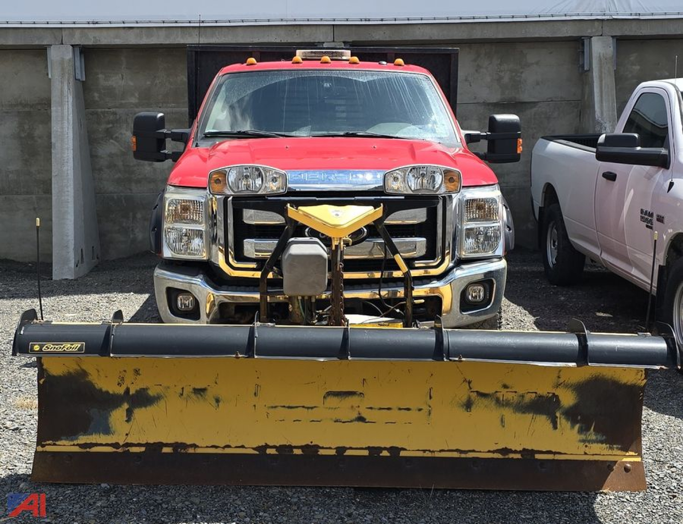 Front view of a red 2016 Ford F-250 Super Duty pickup with a large yellow snow plow attached to the front, two side mirrors, and a chrome grille; utility truck setup in a lot.