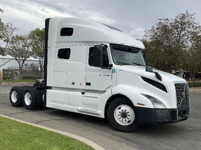 Volvo VNL 760 tractor cab in-service exterior view showing side profile and front grille with sleeper cab, white paint, dual rear axles.