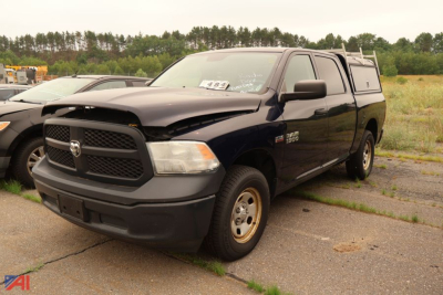 Ram 1500 pickup truck with cap, dark blue, front-left view. Badge on grille, RAM emblem, dual cab, pickup bed with cap. Plate area and front bumper visible.