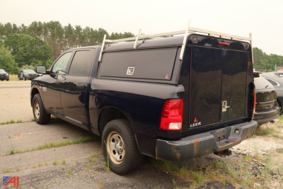 Truck bed side with cap showing tail lights and ladder rack. Visible text includes RAM 4x4 badge and Laramie/LB? not clear. No specific model numbers readable.