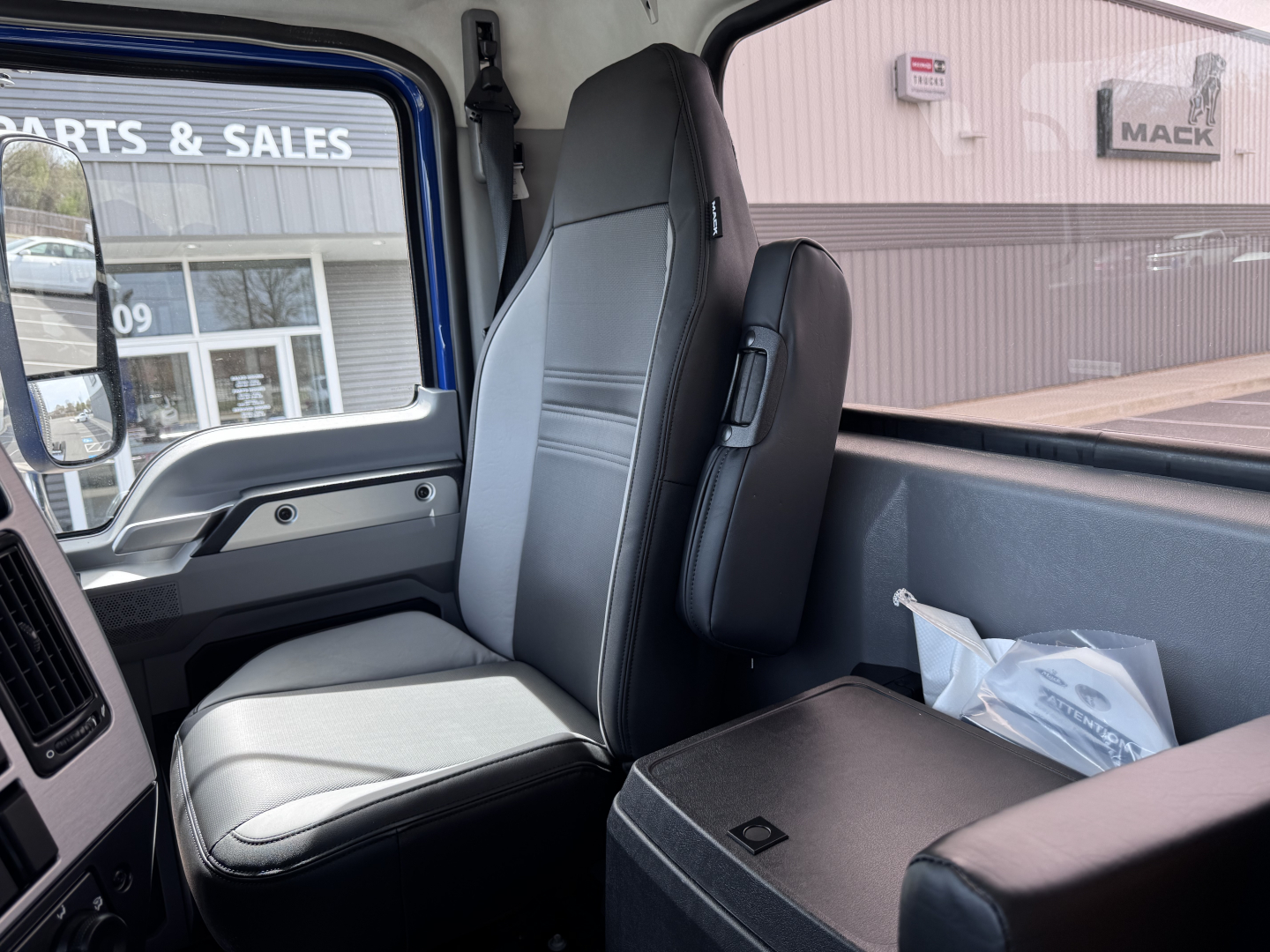 Truck cab interior showing driver and passenger seats with center console and side window