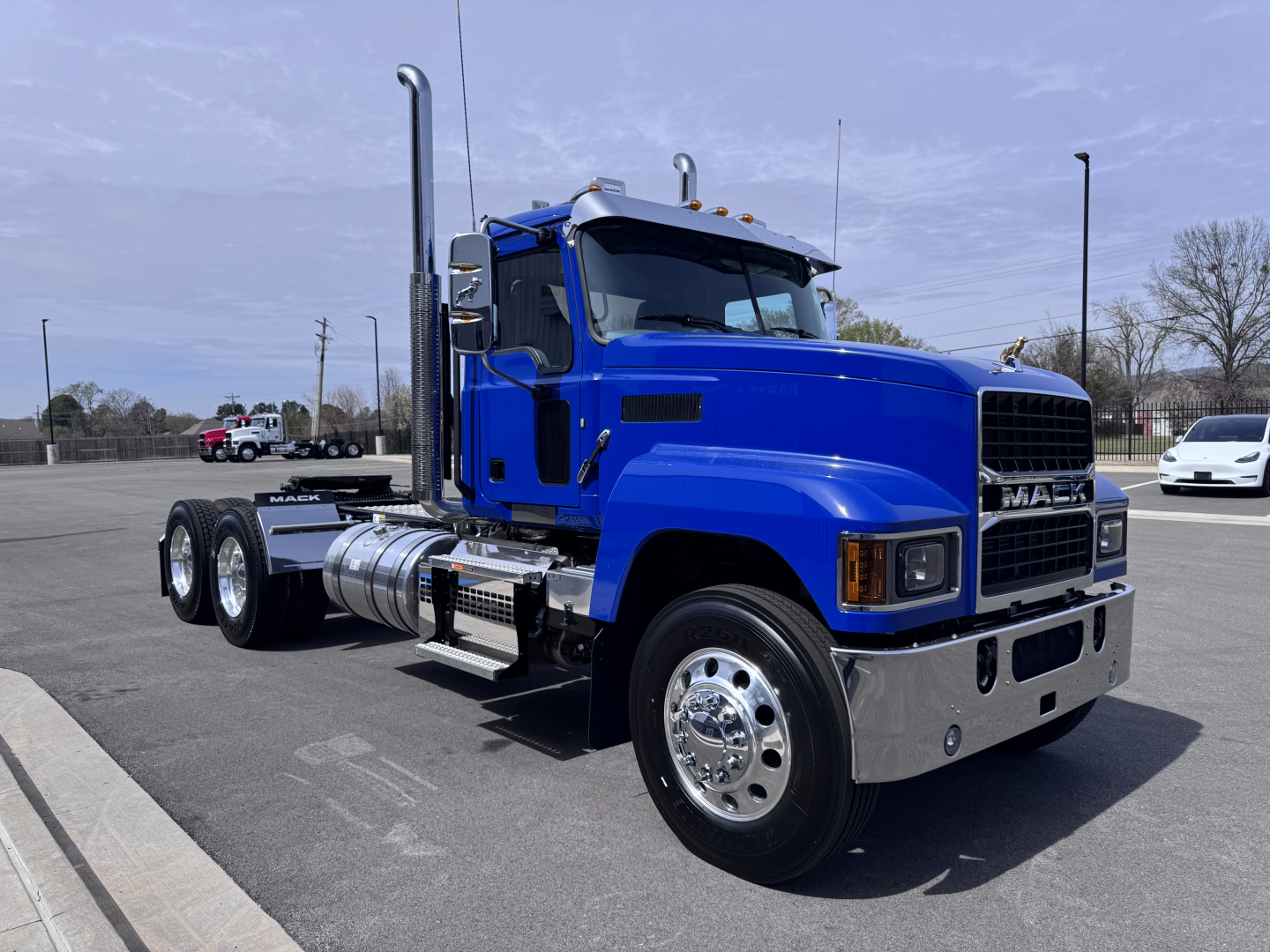 Mack PI64T conventional daycab truck in blue front-left side view showing cab, large grille, dual rear axles, chrome bumper, and exhaust stacks.