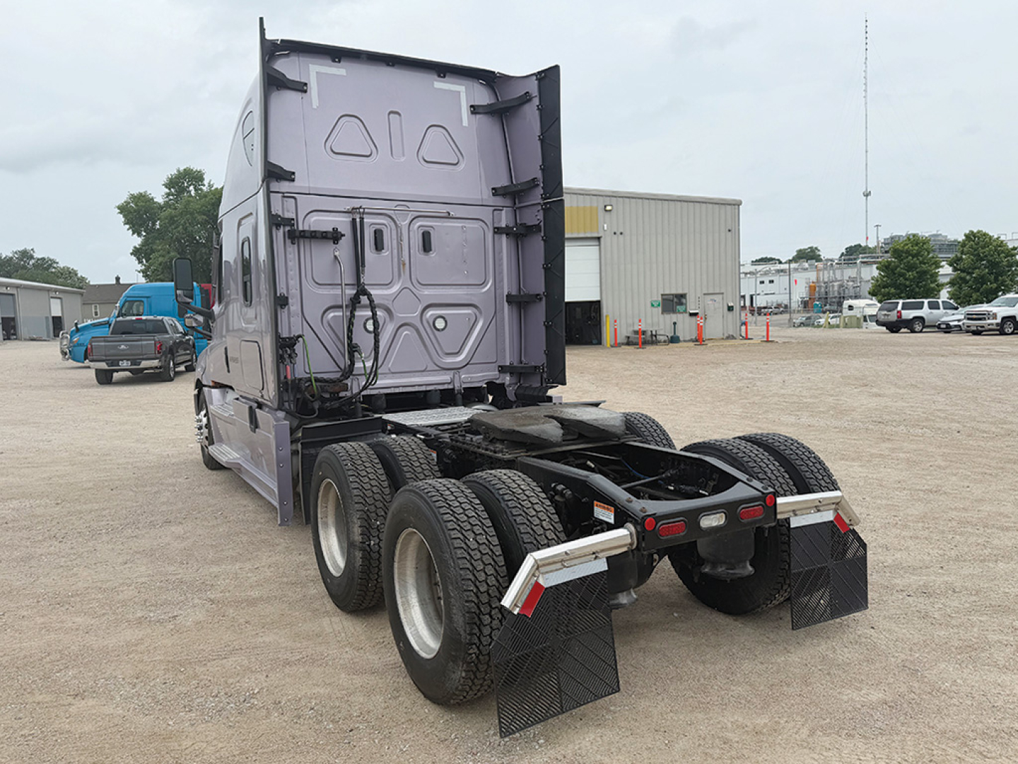 Tractor at a truck yard showing rear view of a Freightliner Cascadia126 sleeper tractor with dual rear axles and mudflaps.