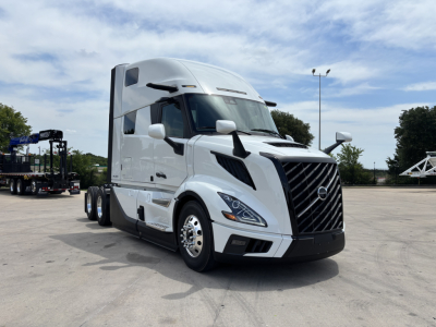 Volvo VNL64T860 conventional sleeper truck in a parking lot, front three-quarter view, white exterior with black grille and aerodynamic mirrors.