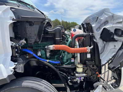 Volvo VNL64T860 engine bay showing diesel engine with orange coolant hose, blue hose, and various components.