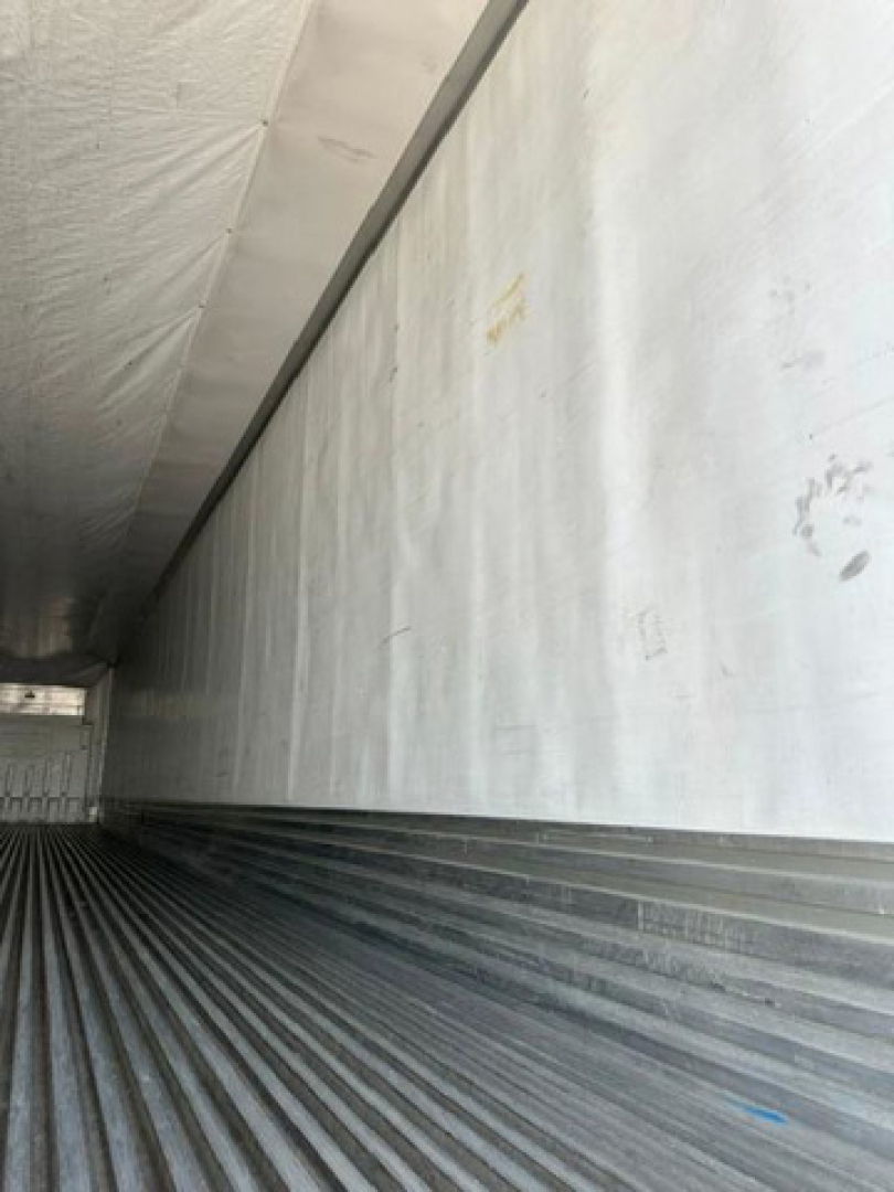 Trailer interior showing metal sidewall and ribbed floor of a refrigerated trailer.