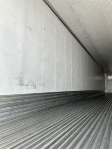 Trailer interior cargo bay of a 2016 utility reefer showing ribbed metal floor and smooth side walls.