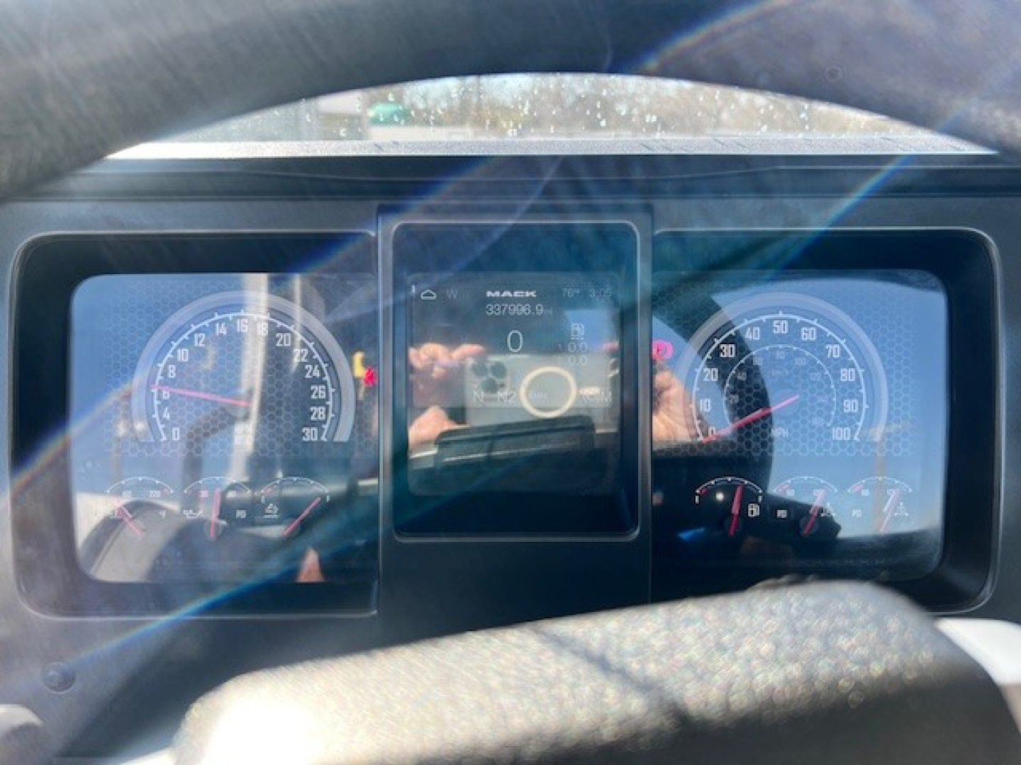 Dashboard view of a Mack AN42T showing gauges and a central digital display with text ‘MACK’ and numbers. 