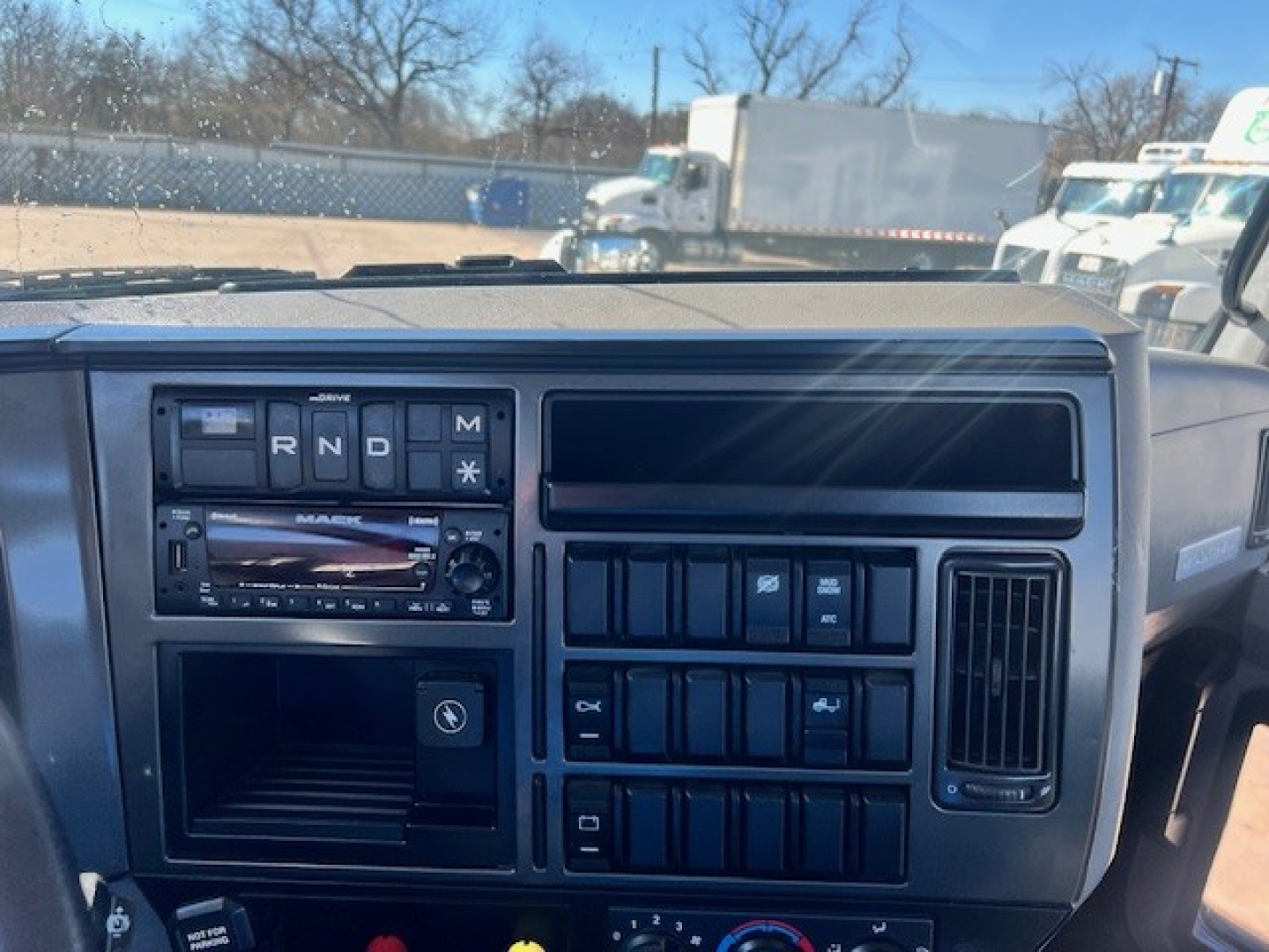 Truck dashboard of a 2022 Mack AN42T showing gear selector (R N D M), radio, and multiple controls