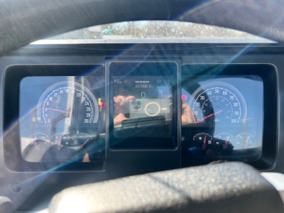Dashboard view of a Mack AN42T showing gauges and a central digital display with text ‘MACK’ and numbers. 