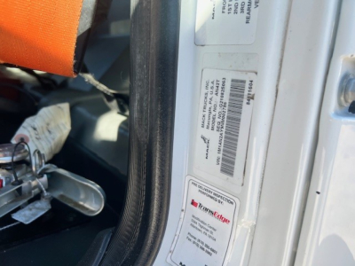 Truck door frame showing VIN/sticker label with barcode and TransEdge service tag inside, cab interior visible near door jamb.