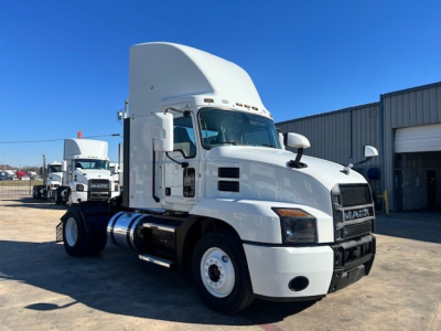 Truck cab of a 2022 Mack AN42T conventional daycab showing front grille, headlights, and raised sleeper; white exterior with black bumper and fuel tanks.