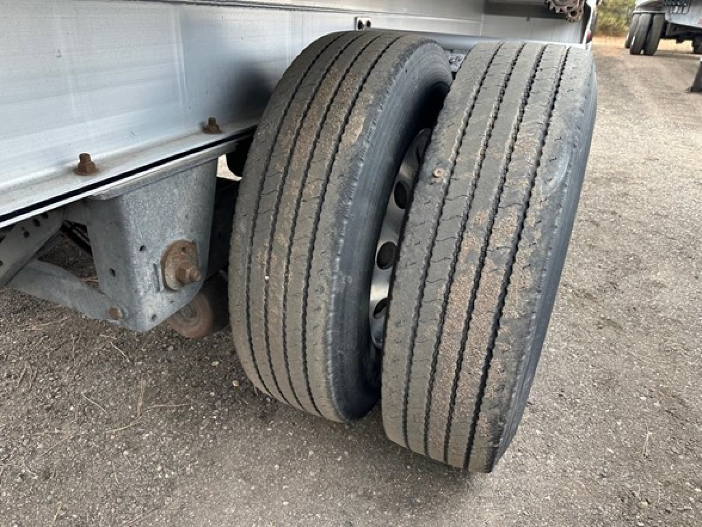 Trailer axle with dual tires on a Mac All Aluminum flatbed showing worn tread on both rear tires.