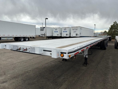 Flatbed trailer showing long aluminum deck with dual-axle rear, front jack, and side markers.