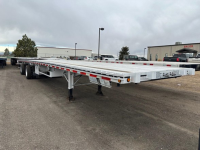 Flatbed trailer showing aluminum deck and tandem axles with supports and side reflectors.
