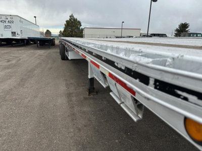 Mac aluminum flatbed trailer showing long side rails, reflective tape, and support legs along the edge.