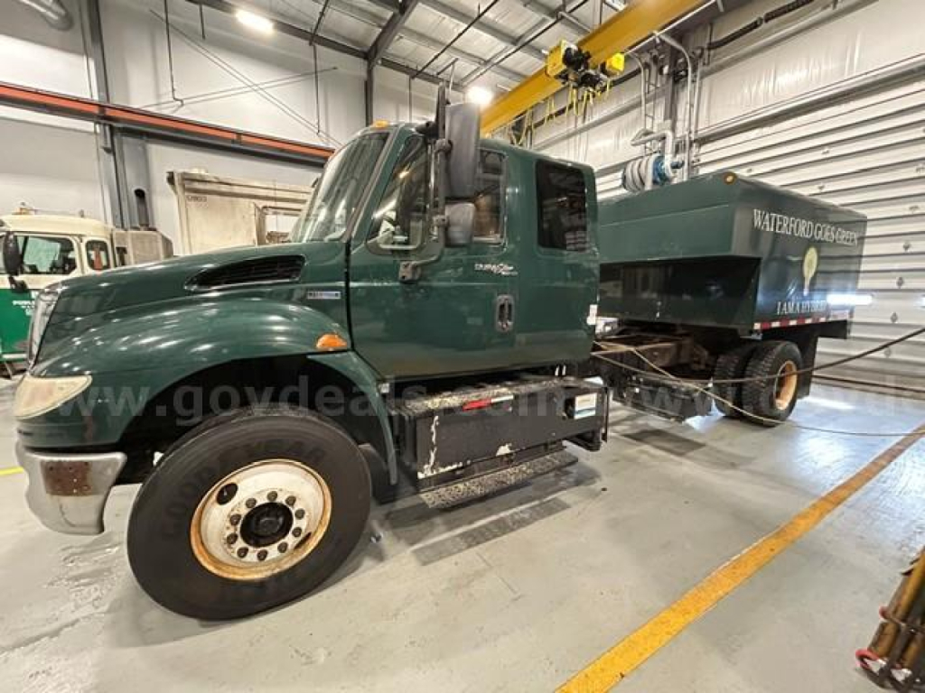 Service/utility truck cab and attached Water/Sludge tank equipment in a warehouse, International 4300, green cab, large front tire, VIN visible.