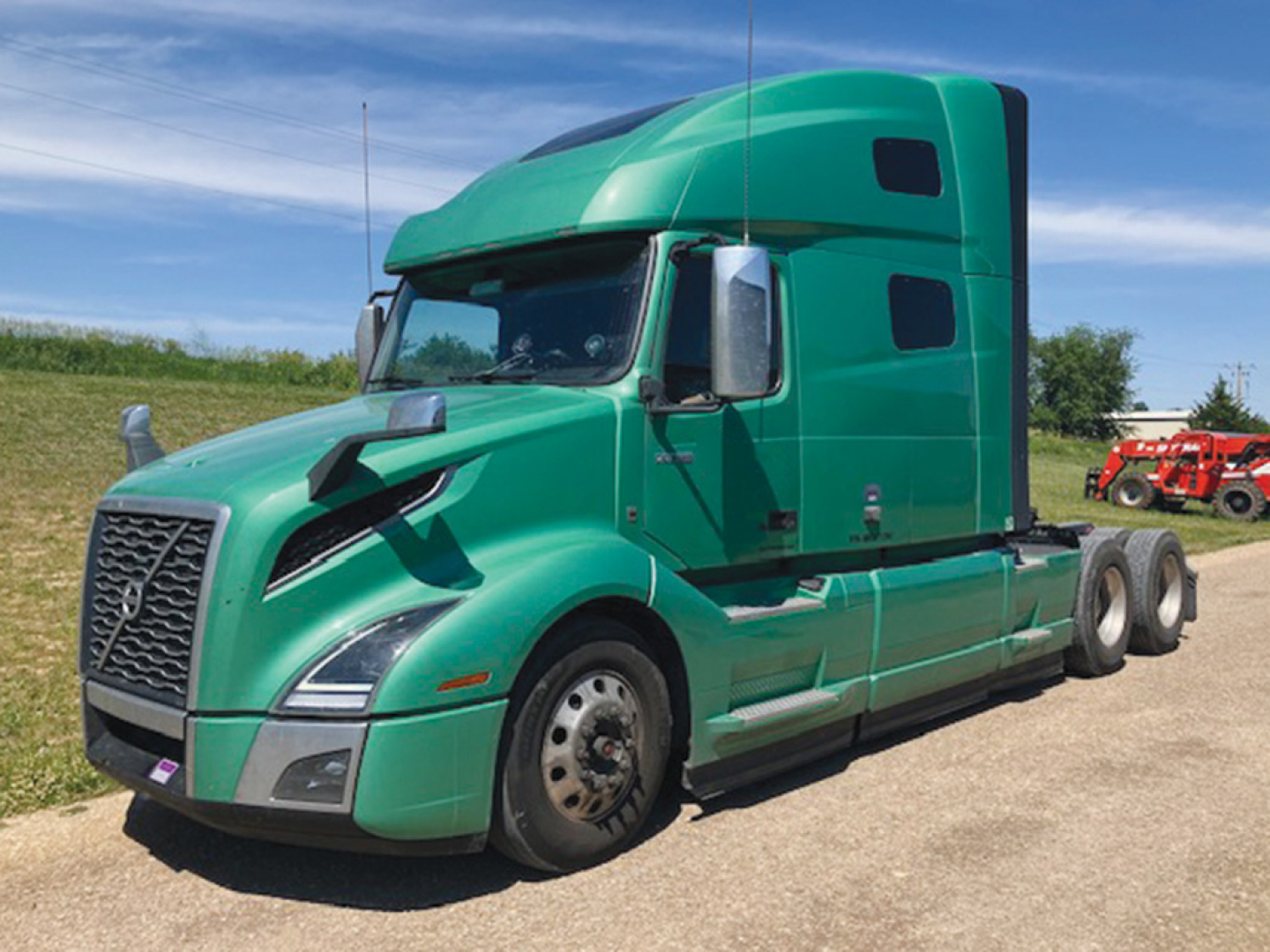 Green Volvo VNL 760 truck side view with sleeper cab, front grille, and dual rear axles.