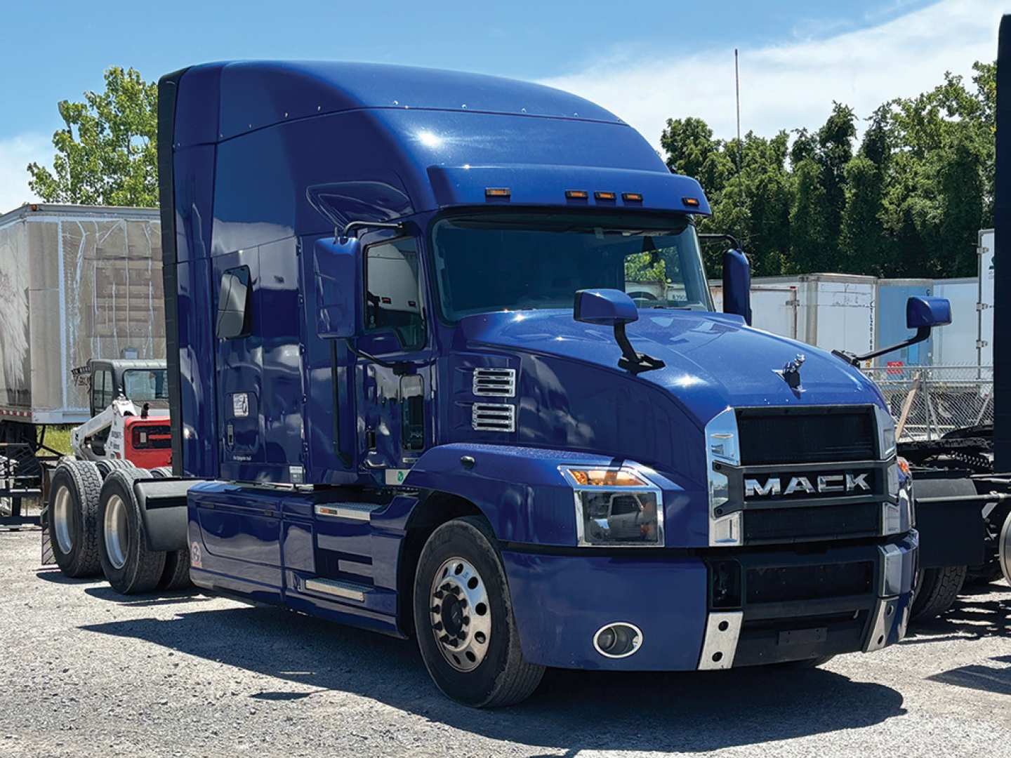 Truck cab front-left view of a blue 2021 Mack Anthem with large grille and dual headlights.