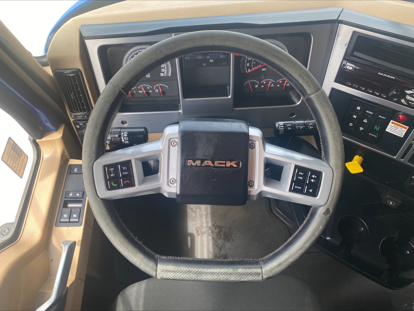 Steering wheel and dashboard of a Mack GR64F truck cab showing instrument cluster and control panels