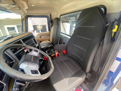 Truck cab interior showing steering wheel, driver seat, and dashboard of a 2019 Mack GR64F, with text on panels and controls visible.