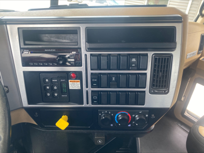 Dashboard console of a 2019 Mack GR64F rolloff truck showing radio, climate controls, and multiple switches. Text visible includes 'MARK', 'PRA', 'R N D', warning sticker, and various switch labels.