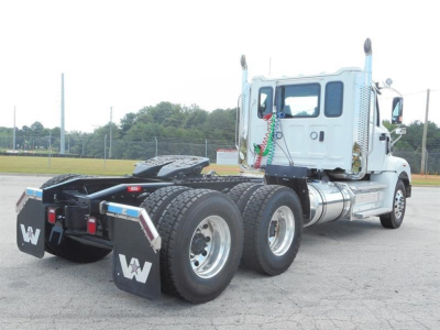 Western Star 49X tractor rear view showing dual rear axles, dual rear tires, and gray cab with chrome fuel tanks; visible safety decals and mud flaps with WT logos.