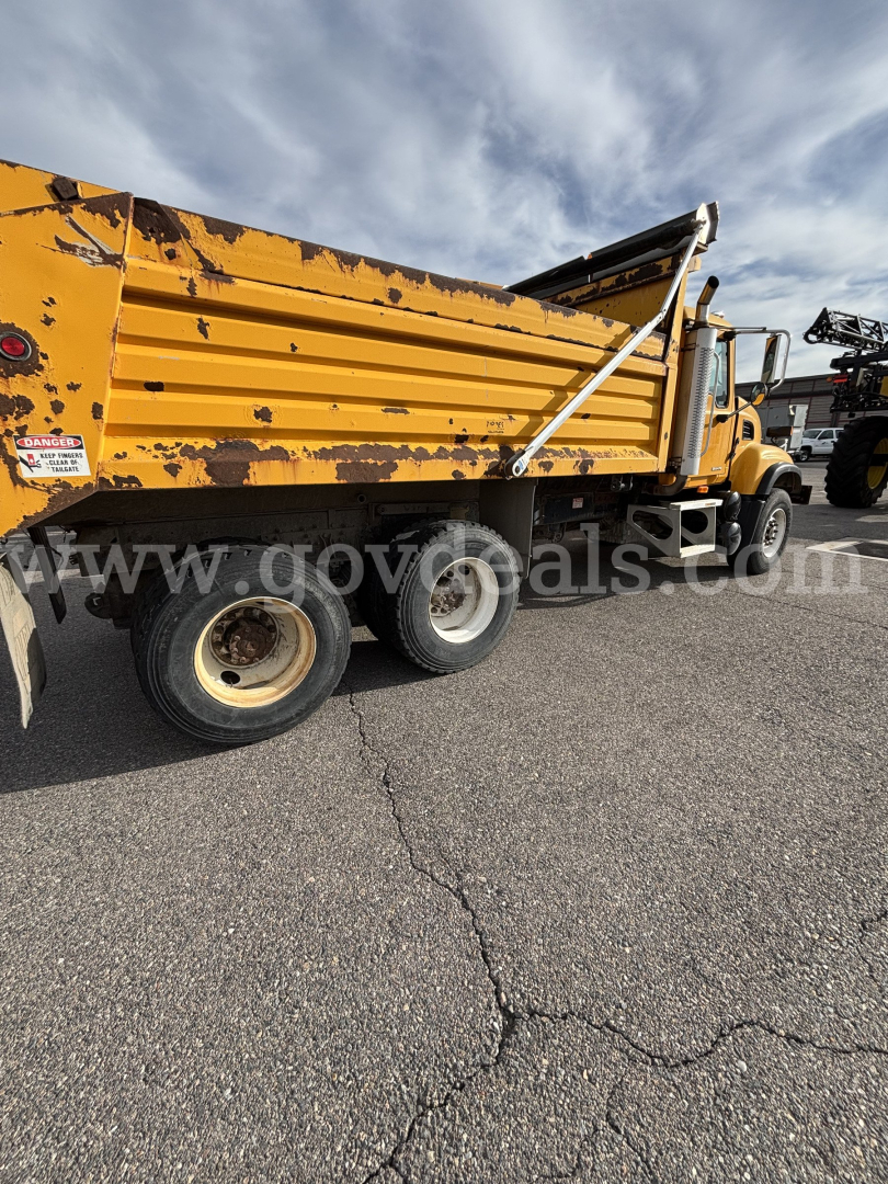 Dump truck side view showing yellow Mack CV713 with scratched paint and cargo bed raised; VIN label visible on cab; stock 8636-766.