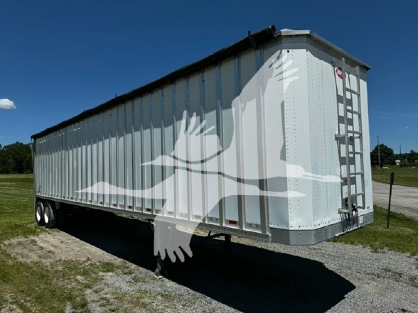 Trailer side view of a 2022 Dorsey Open Top Chip Van with ladder at rear, metal corrugated walls, tri-axle rear. Shows stamped license/brand info on side.