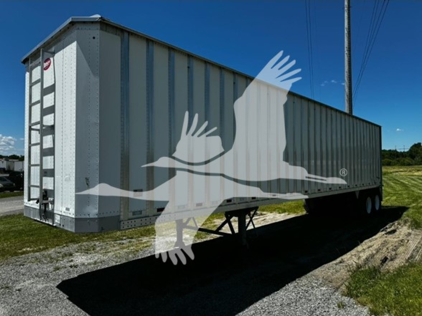 Trailer showing large open-top chip van with metallic sides and rear access, no visible text on sides.