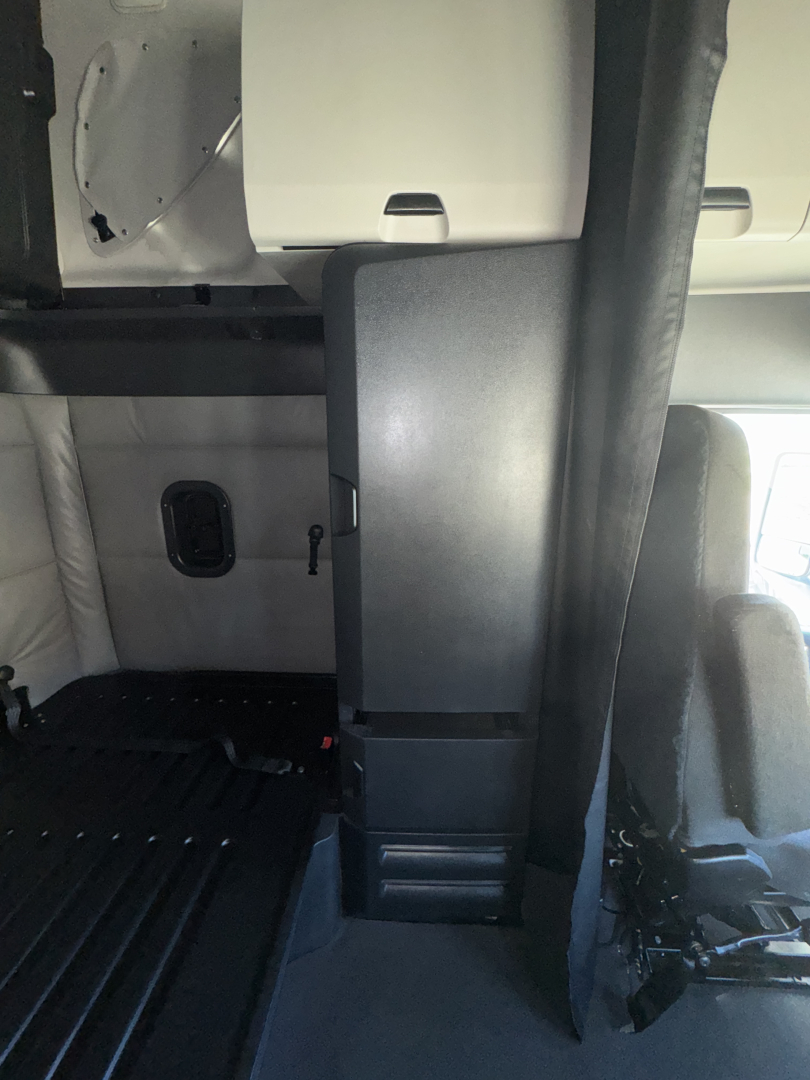 Cab interior of a 2022 Freightliner Cascadia 126 showing cabin partition and driver seat area.