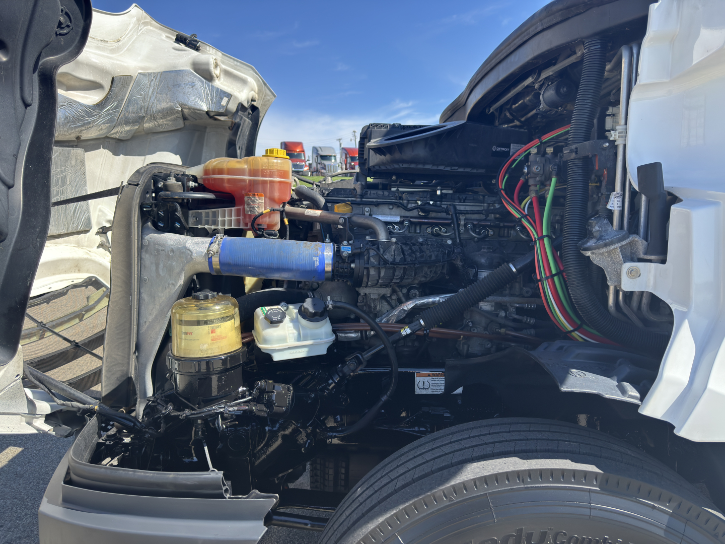 Freightliner Cascadia 126 engine bay sight with visible fluid reservoirs, hoses, and cab components.
