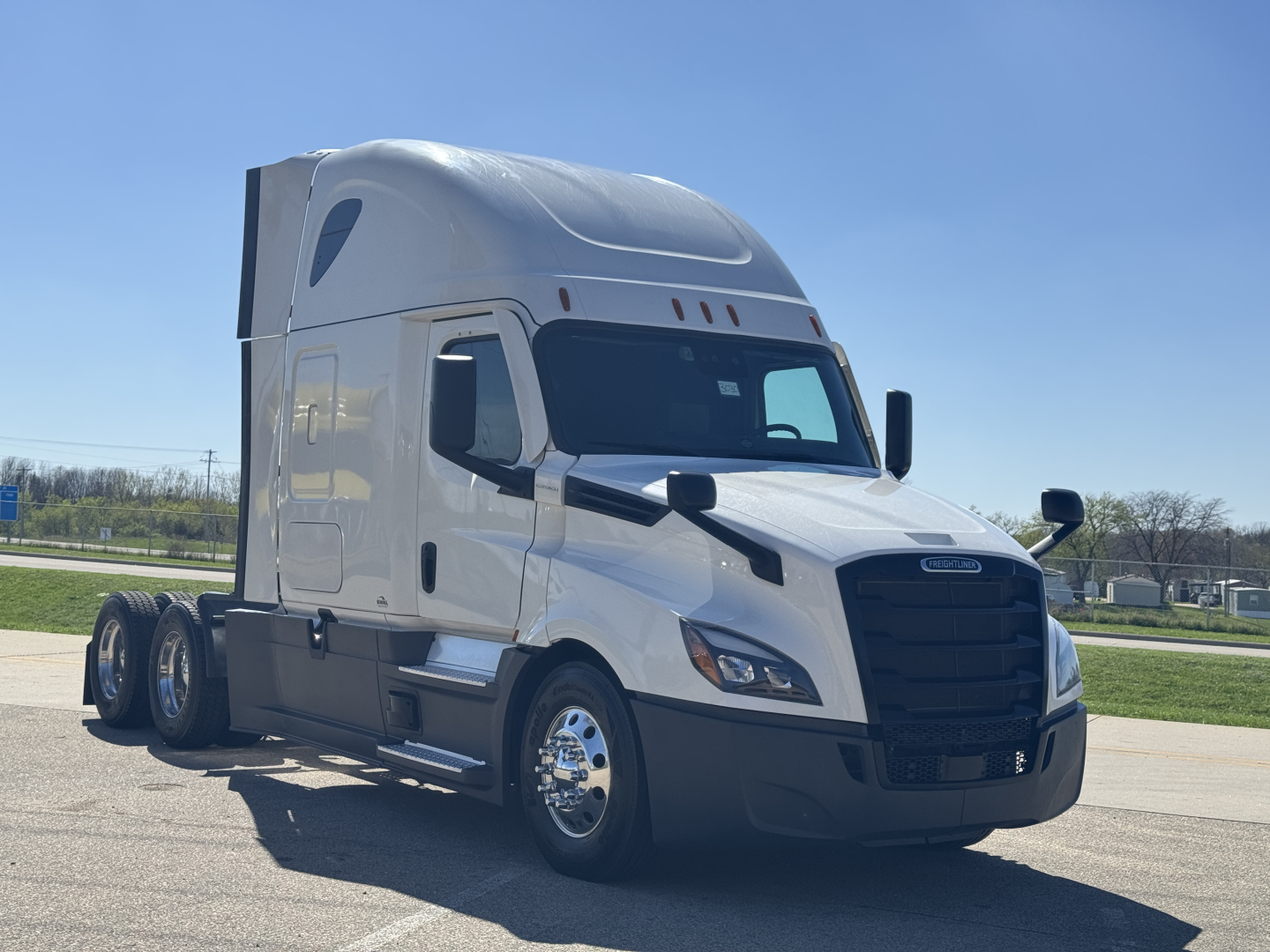 Truck cab in-frame view of a Freightliner Cascadia 126 sleeper tractor showing front grille, bumper, headlights, and side mirrors.