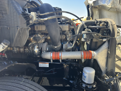 Freightliner Cascadia engine bay showing turbocharger piping and coolant hoses with orange insulated intercooler line and filter canister.