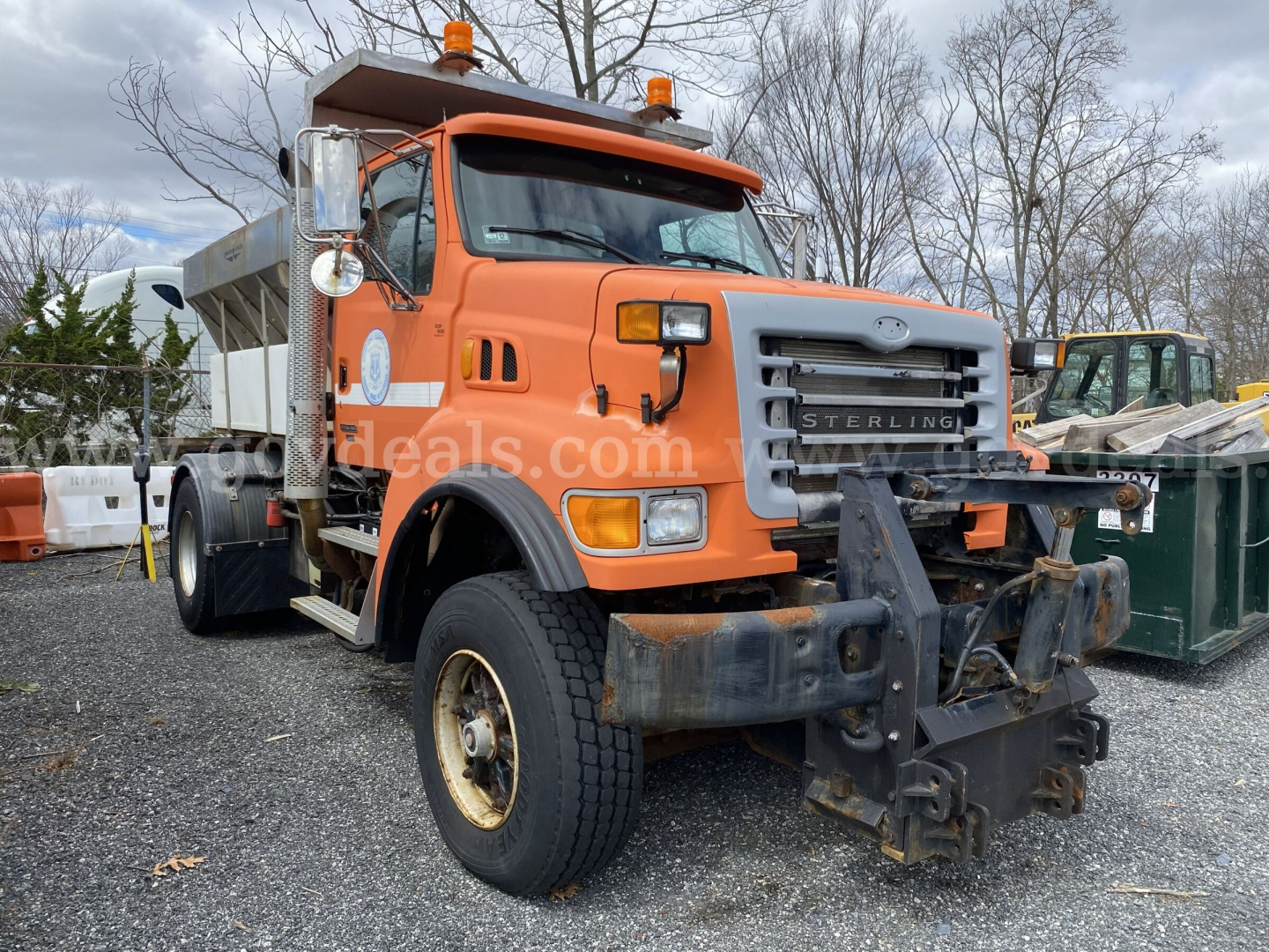Dump truck front view showing Sterling L9500 with snow plow mount and orange cab. Visible text on grille and bumper.