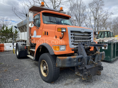 Dump truck front view showing Sterling L9500 with snow plow mount and orange cab. Visible text on grille and bumper.