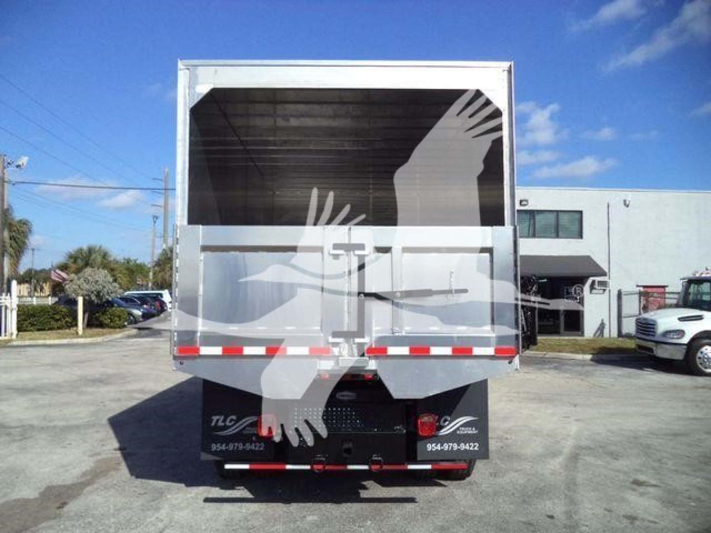 Truck rear view showing the cargo bed of a used 2019 International 4300 with chipper branding and reflective safety stripes.
