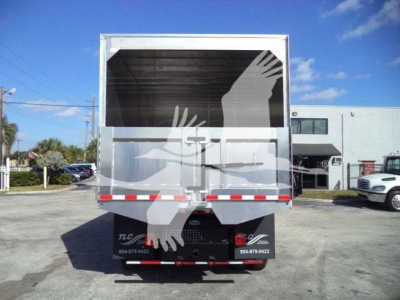 Truck rear view showing the cargo bed of a used 2019 International 4300 with chipper branding and reflective safety stripes.