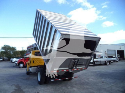 Truck bed dump hopper tilting on a 2019 International 4300 truck showing a yellow cab in a used truck lot.