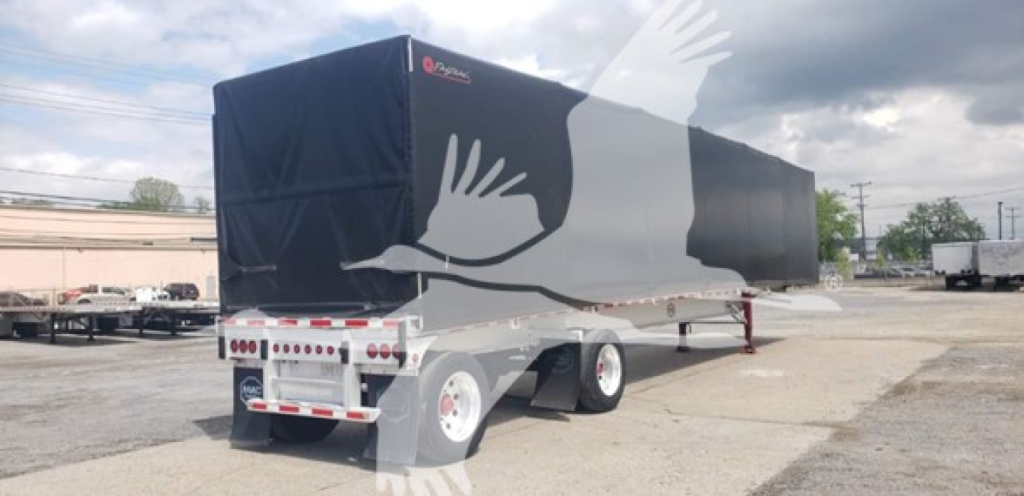 Mac aluminum flatbed trailer with curtainside cover, black tarp, dual rear axles, viewed from rear-left side.