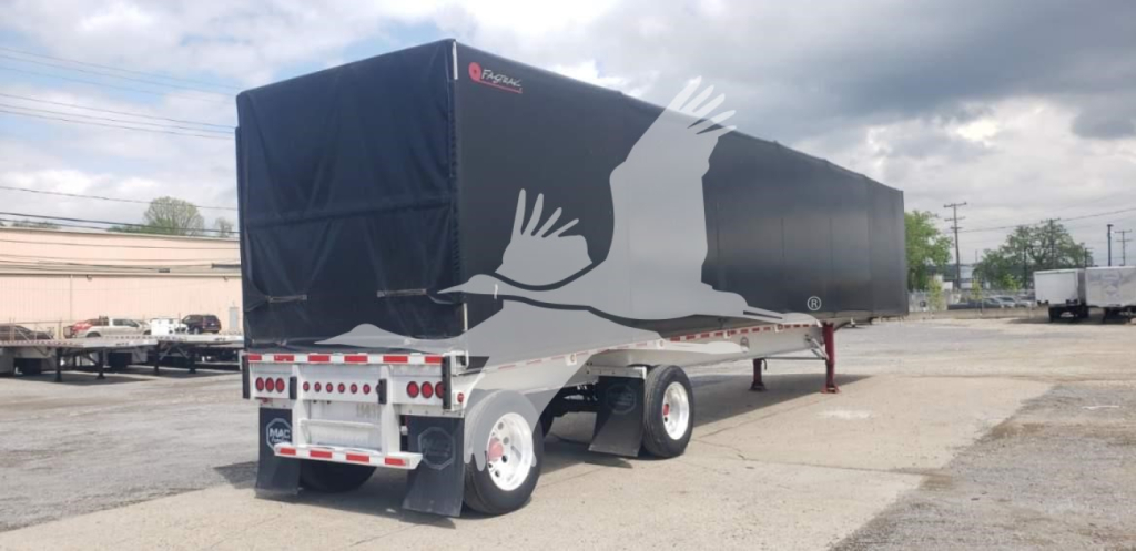 Curtainside trailer with black tarp cover and white graphic of a bird in flight. Dual rear axle, covered load area, trailer landing gear visible.