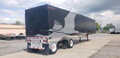 Curtainside trailer with black tarp cover and white graphic of a bird in flight. Dual rear axle, covered load area, trailer landing gear visible.