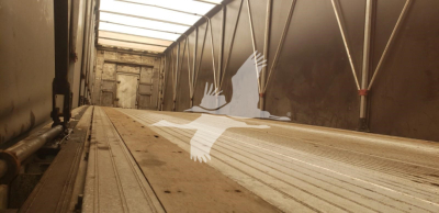 Trailer interior showing empty aluminum cargo floor with rails and wheel wells along the sides.