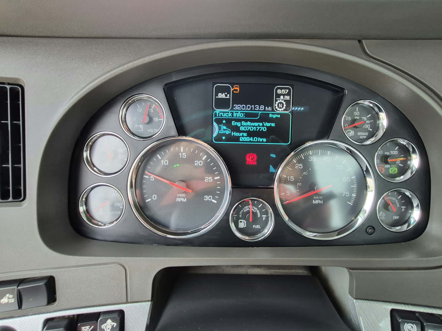 Dashboard view of a Kenworth T880 instrument cluster showing various gauges and a central digital display.