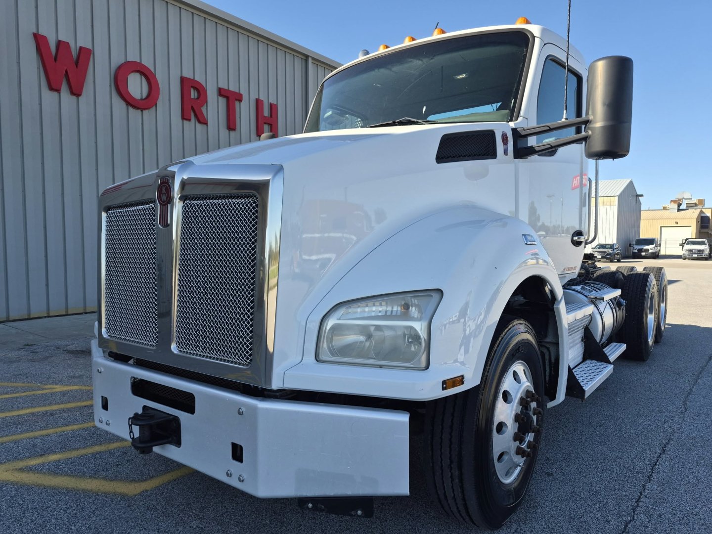 Kenworth T880 daycab truck in white front left side view showing grille, bumper, headlights, large side mirrors and fuel tanks.