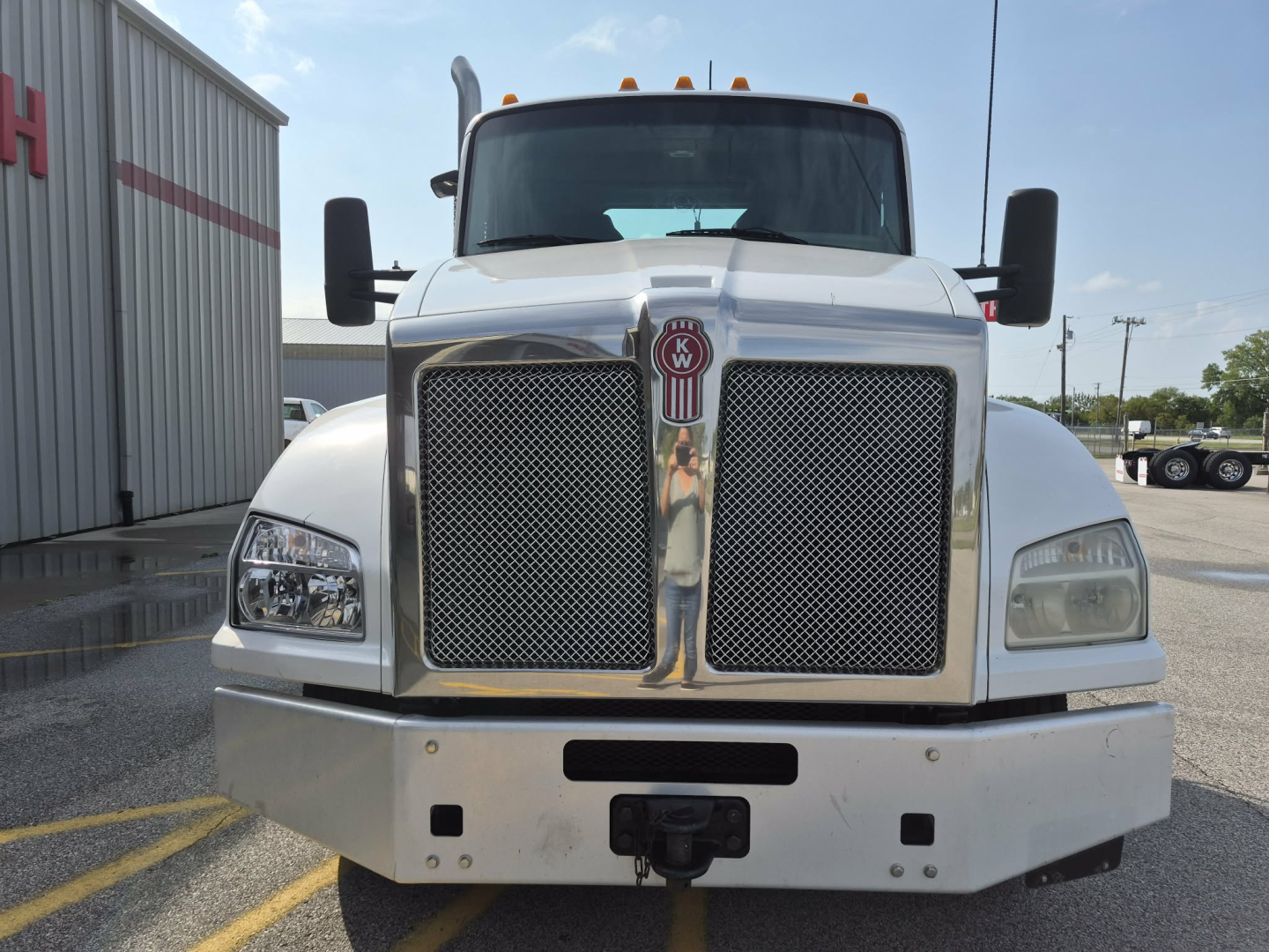 Front view of a white 2018 Kenworth T880 conventional daycab truck showing large chrome grille, bumper, and black side mirrors.