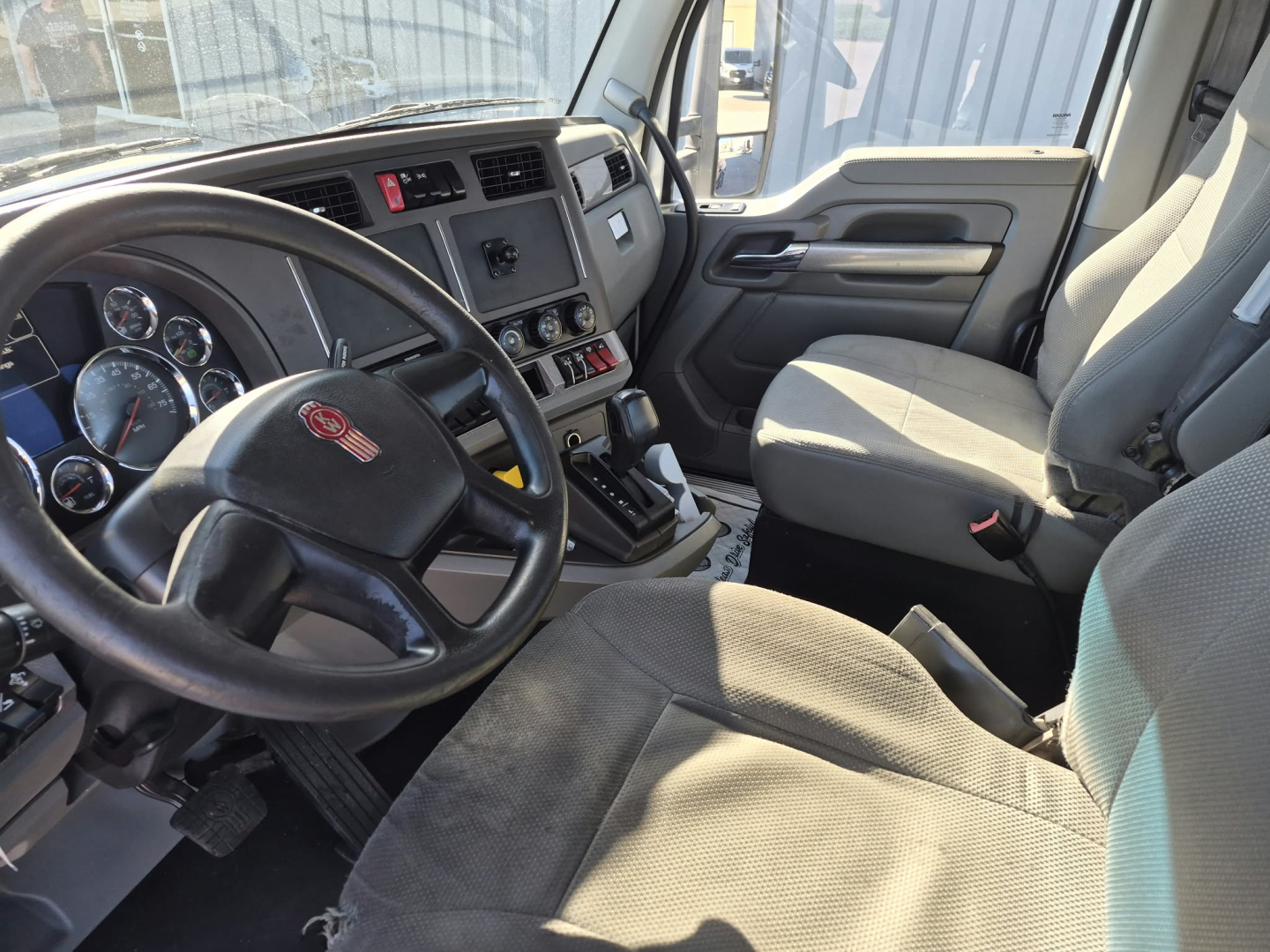 Kenworth T880 truck interior with steering wheel, dashboard gauges, gear shifter, and front seats visible.