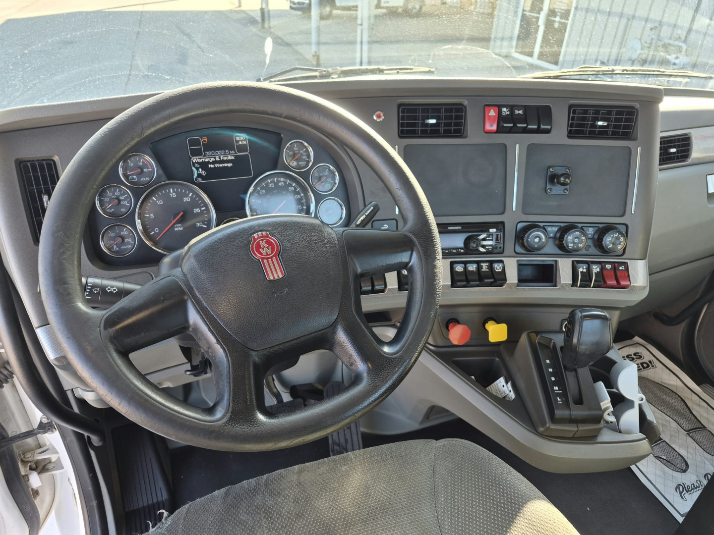 Kenworth T880 truck interior cockpit with steering wheel, dashboard gauges, control switches, and gear shifter.